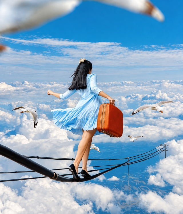 Une femme en équilibre sur des câbles au-dessus des nuages, une valise à la main